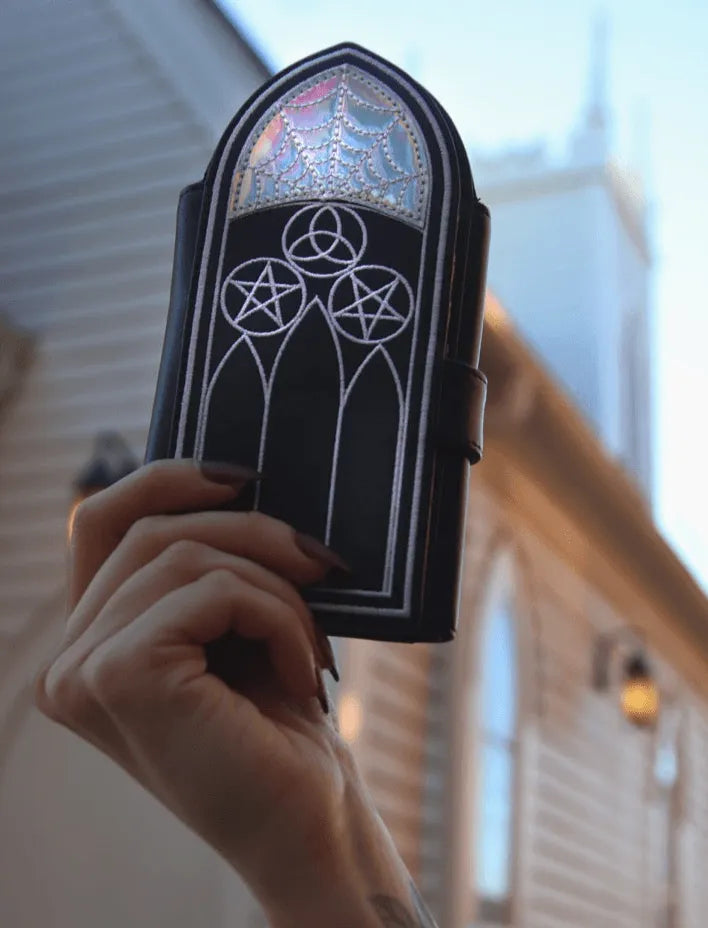 A black wallet featuring Gothic inspired architecture. The top has a holographic spiderweb design.