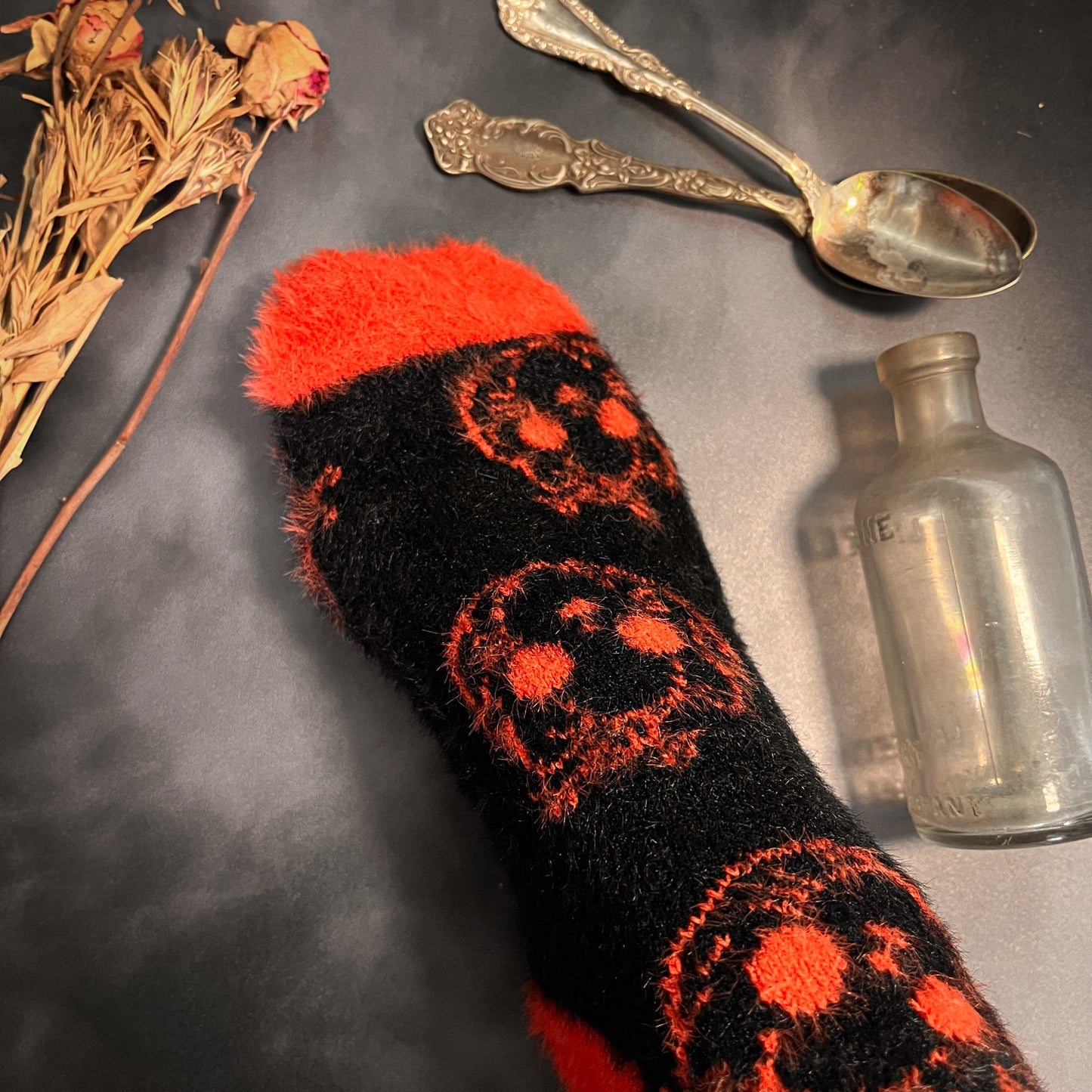 Black fuzzy socks with orange on the toe, heel, and ankle featuring a pattern of pumpkin shaped cat heads.