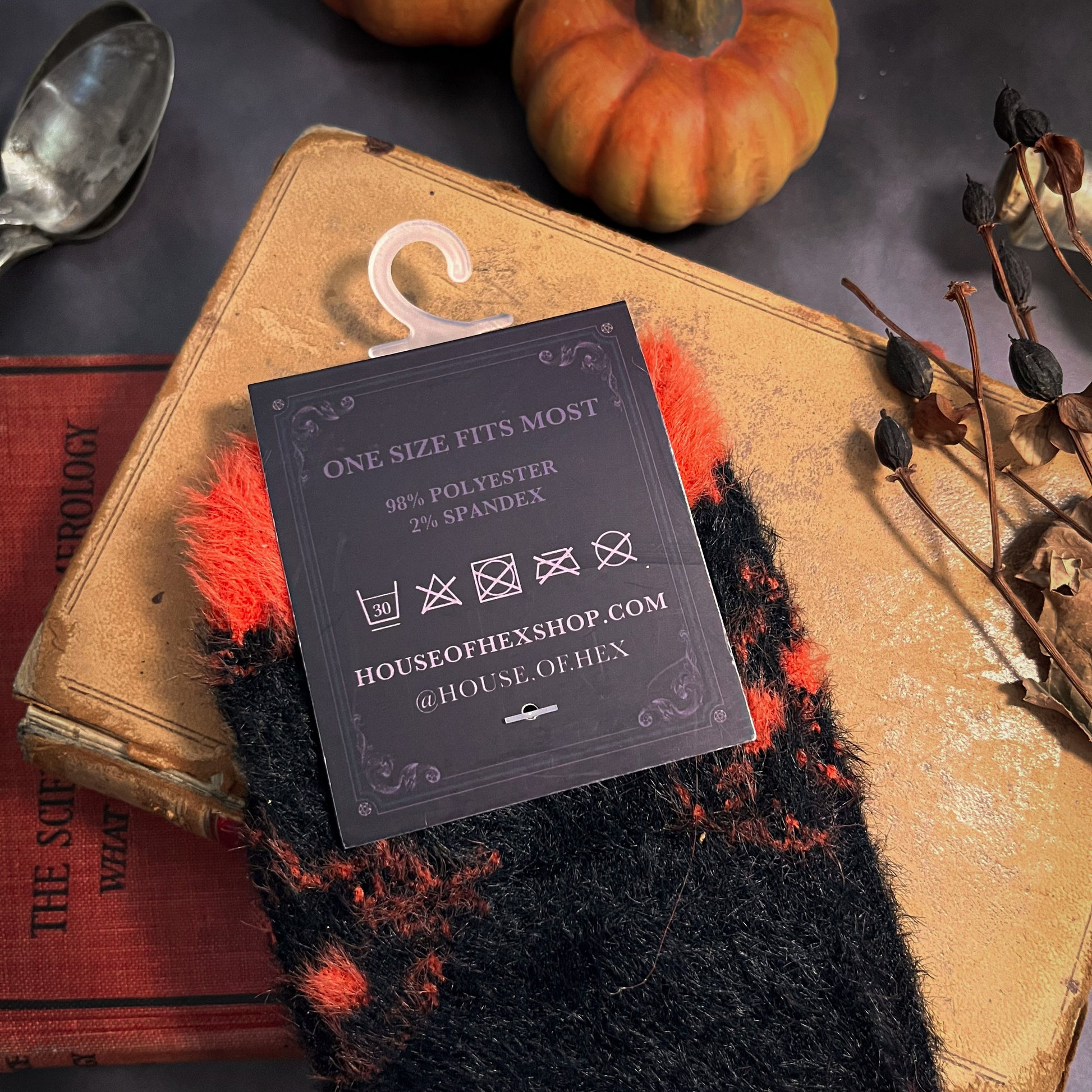 Black fuzzy socks with orange on the toe, heel, and ankle featuring a pattern of pumpkin shaped cat heads.