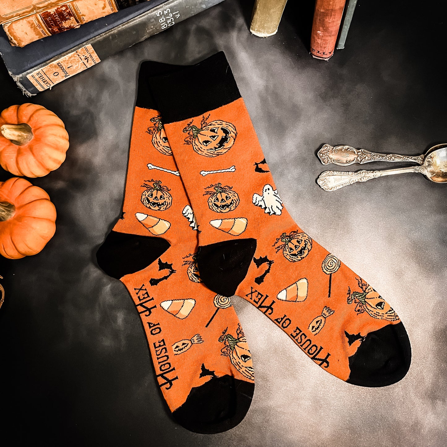 Halloween socks with blacks on the toes, heel, and ankle section featuring a pattern of pumpkins, candy corn, ghosts, bones, and bats.