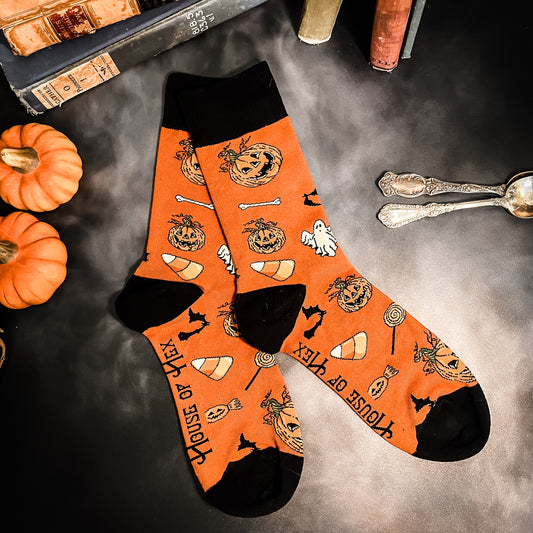 Halloween socks with blacks on the toes, heel, and ankle section featuring a pattern of pumpkins, candy corn, ghosts, bones, and bats.