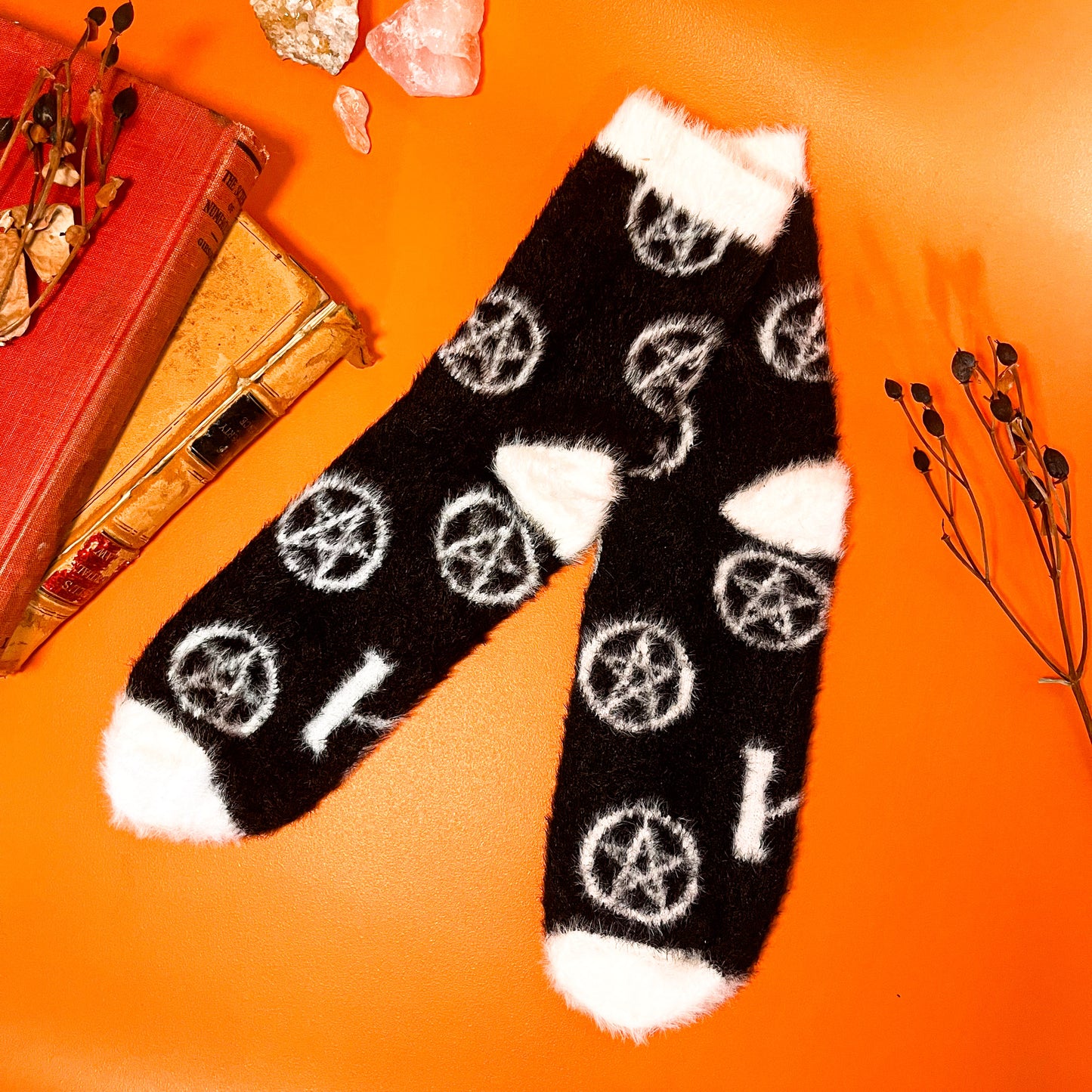 Black fuzzy socks with white on the toe, heel, and ankle featuring a pattern of pentagrams.