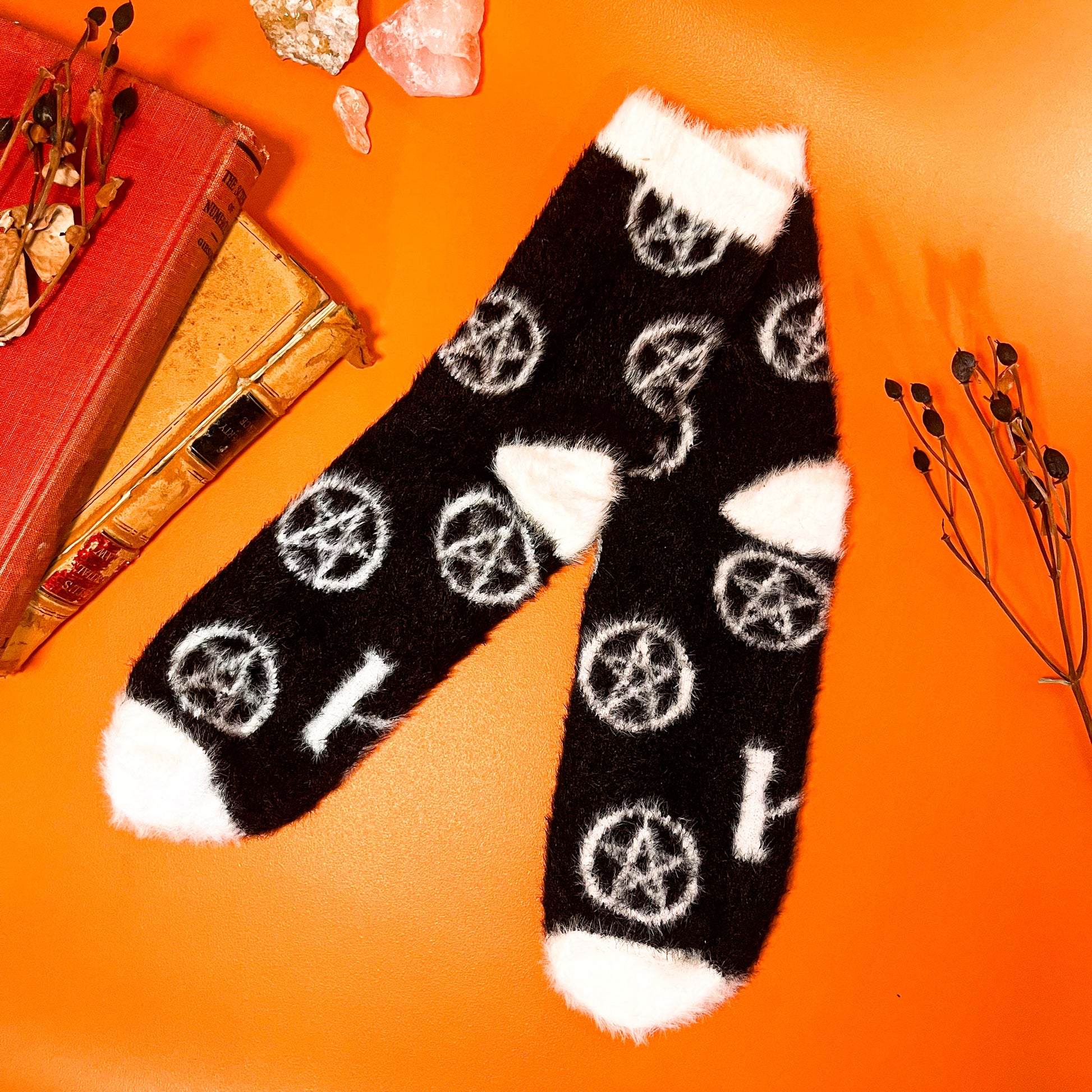 Black fuzzy socks with white on the toe, heel, and ankle featuring a pattern of pentagrams.