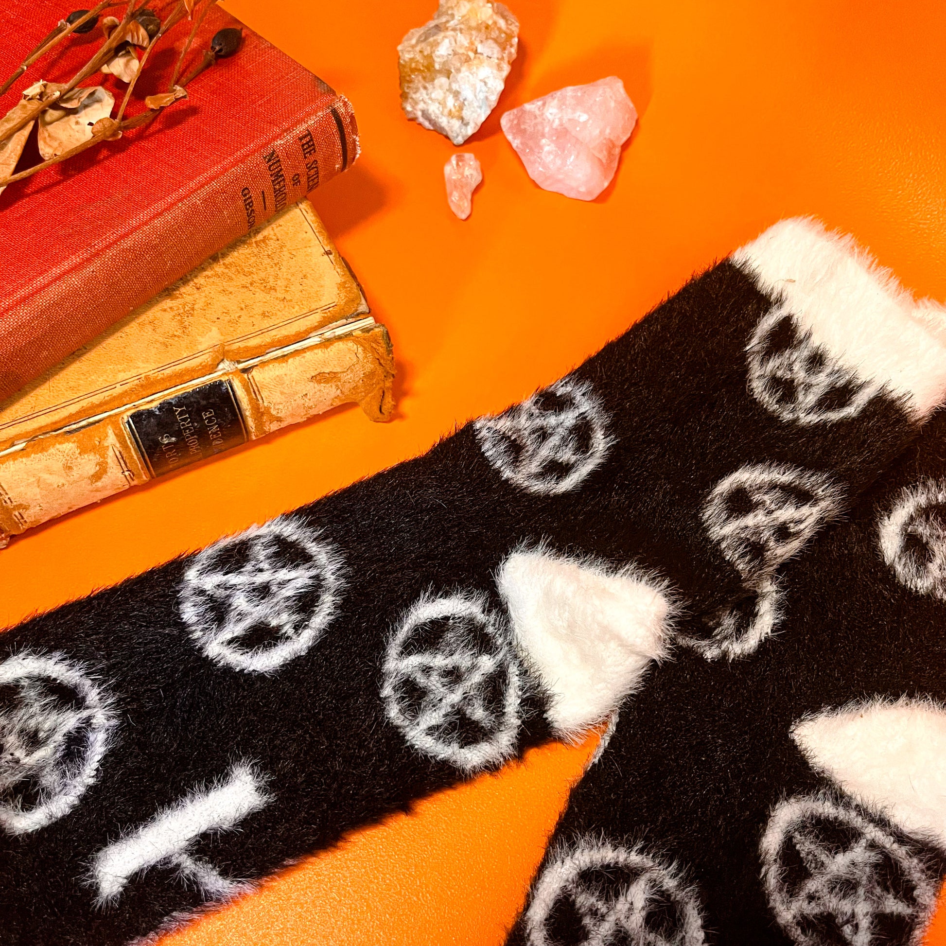 Black fuzzy socks with white on the toe, heel, and ankle featuring a pattern of pentagrams.