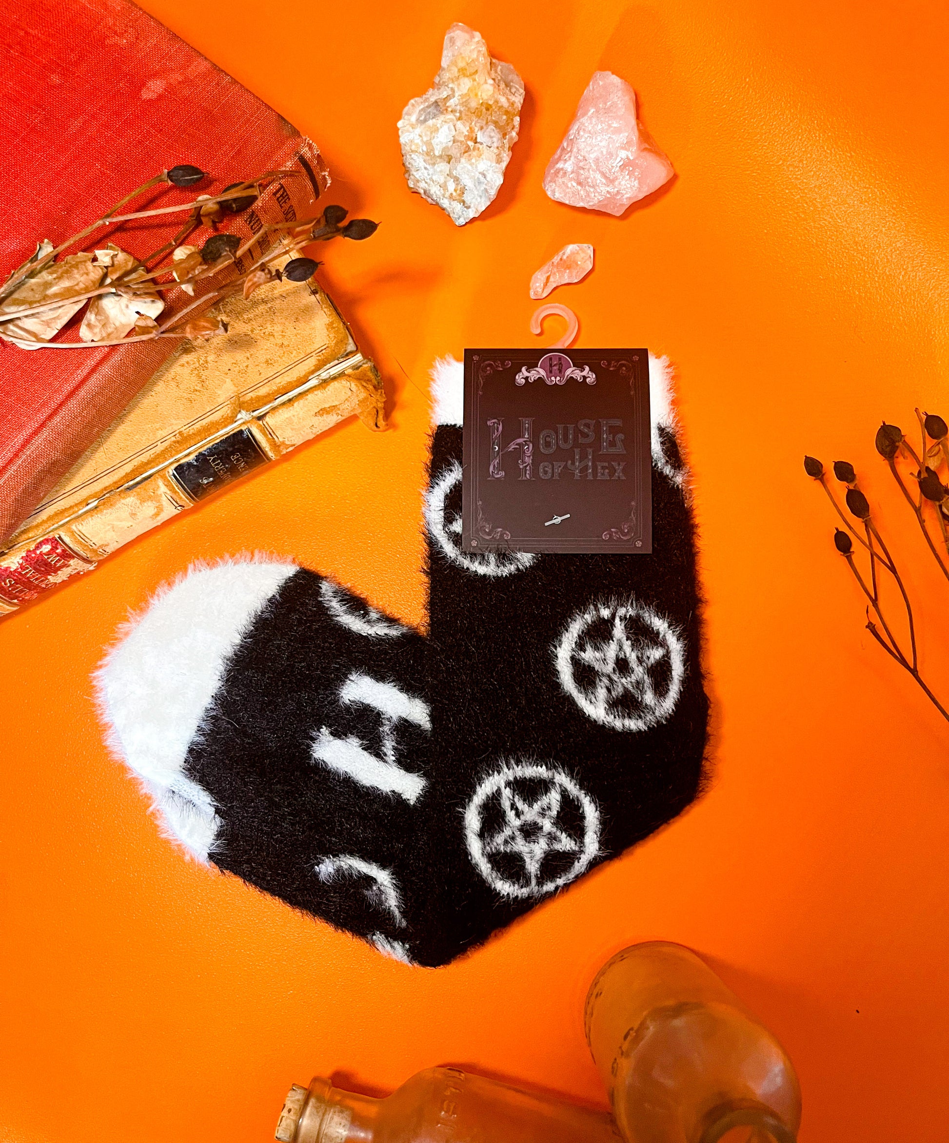 Black fuzzy socks with white on the toe, heel, and ankle featuring a pattern of pentagrams.