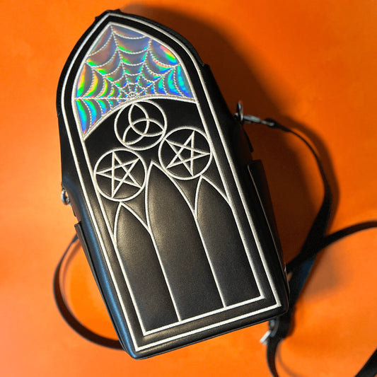 A black purse featuring Gothic inspired architecture. The top has a holographic spiderweb design.