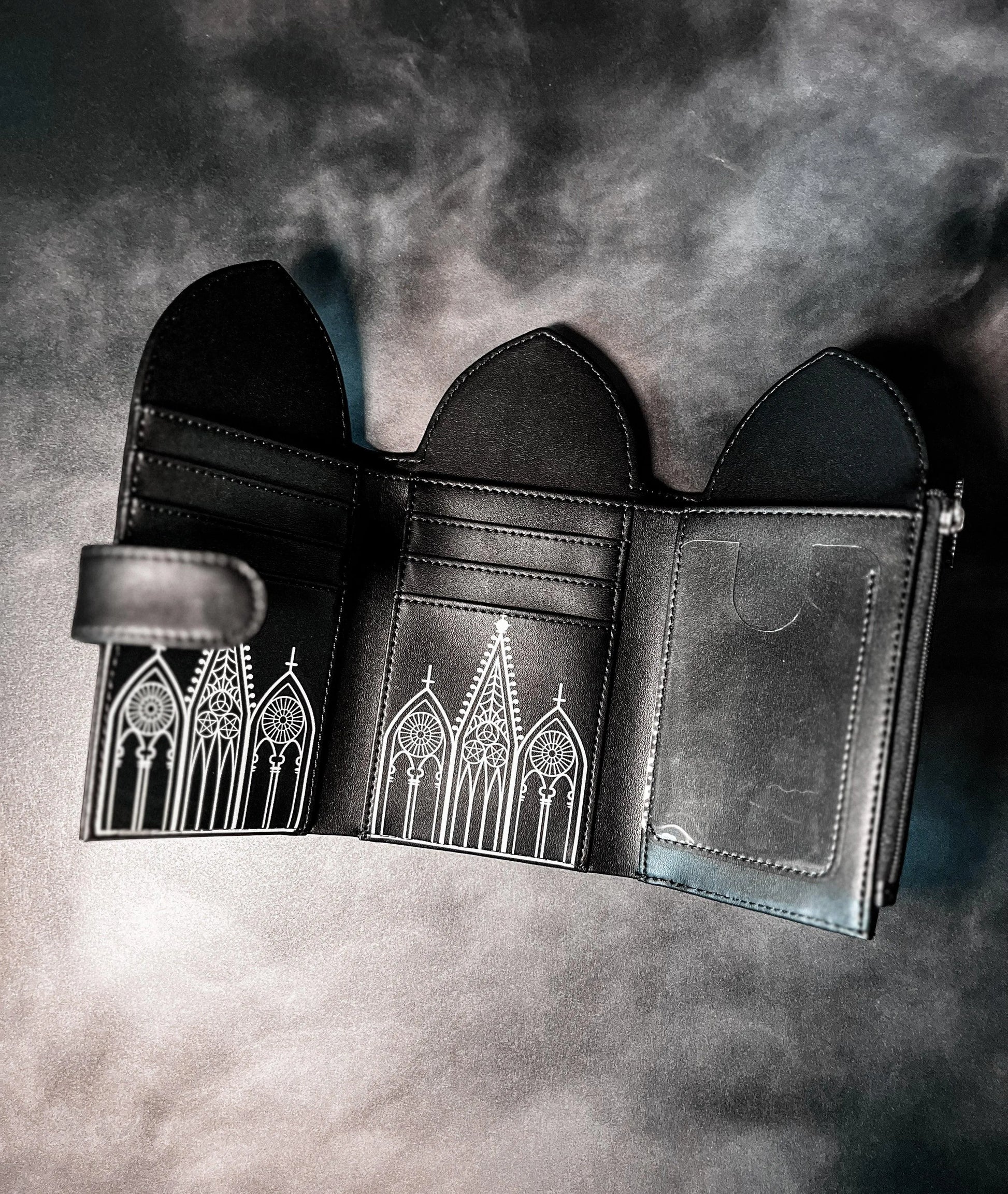 A black wallet opened up in a tri-fold style featuring Gothic inspired architecture.
