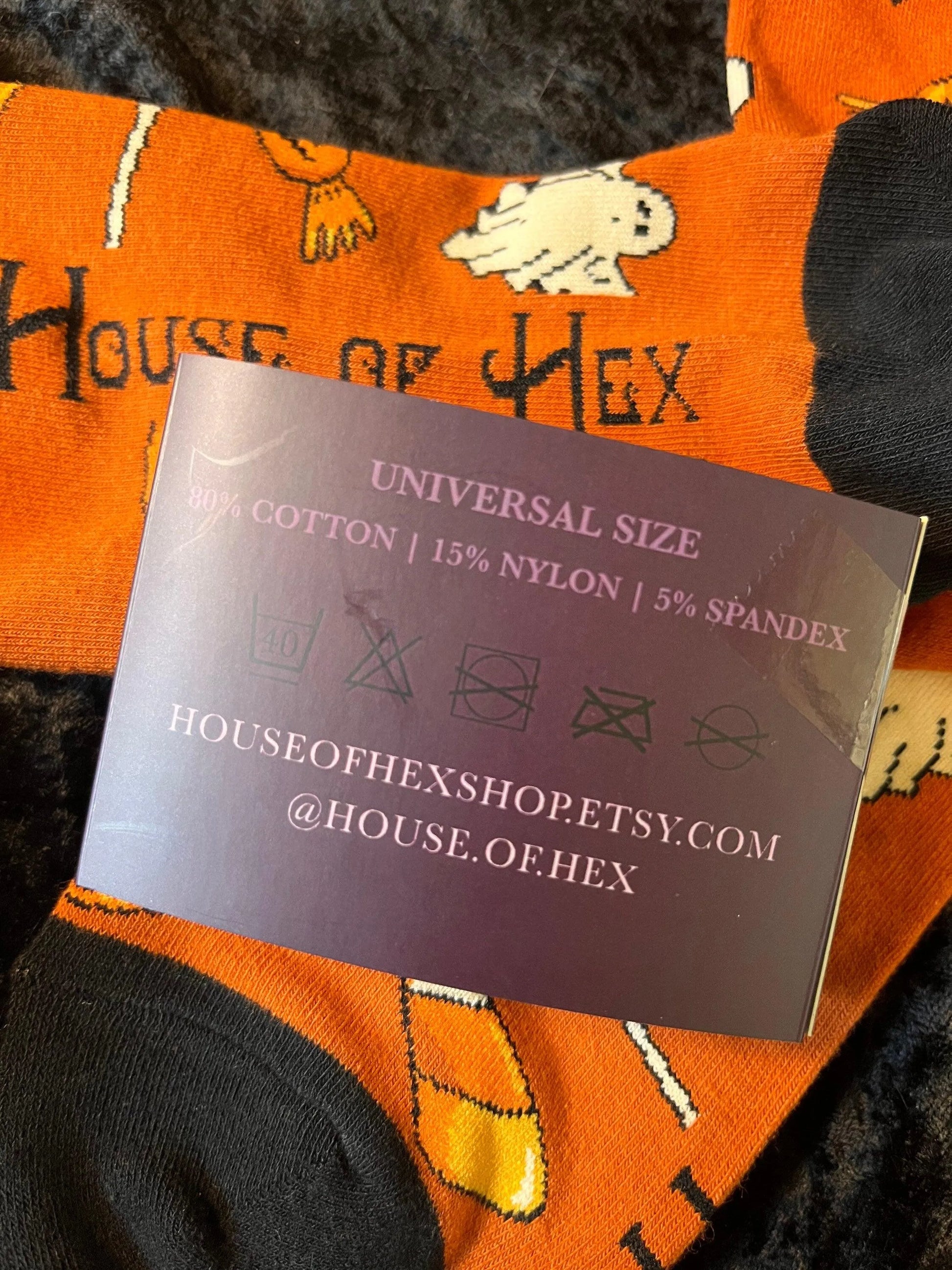 Halloween socks with blacks on the toes, heel, and ankle section featuring a pattern of pumpkins, candy corn, ghosts, bones, and bats.