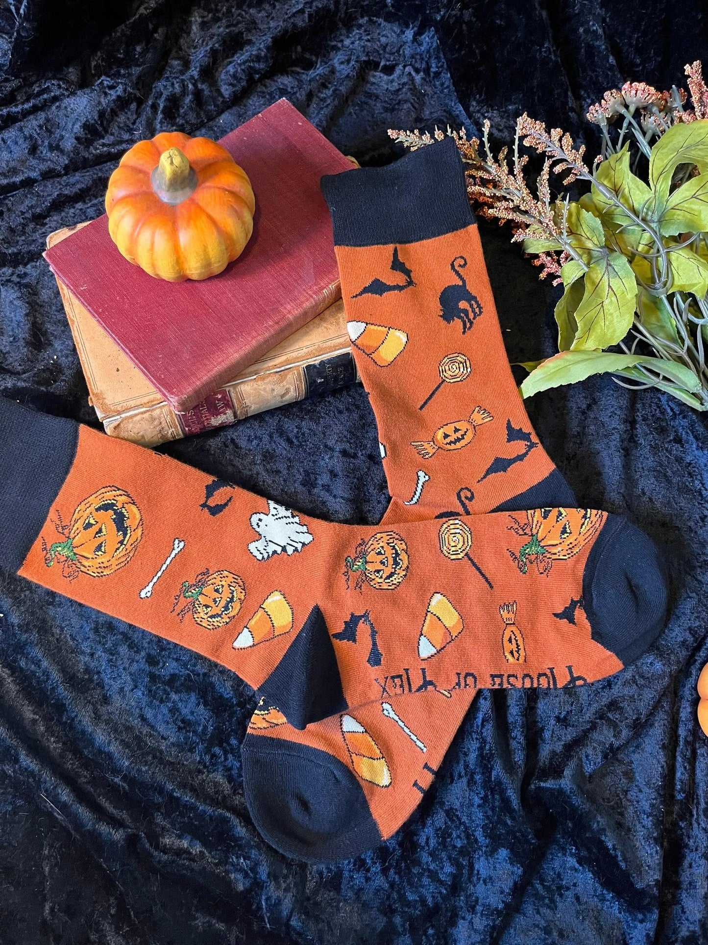 Halloween socks with blacks on the toes, heel, and ankle section featuring a pattern of pumpkins, candy corn, ghosts, bones, and bats.