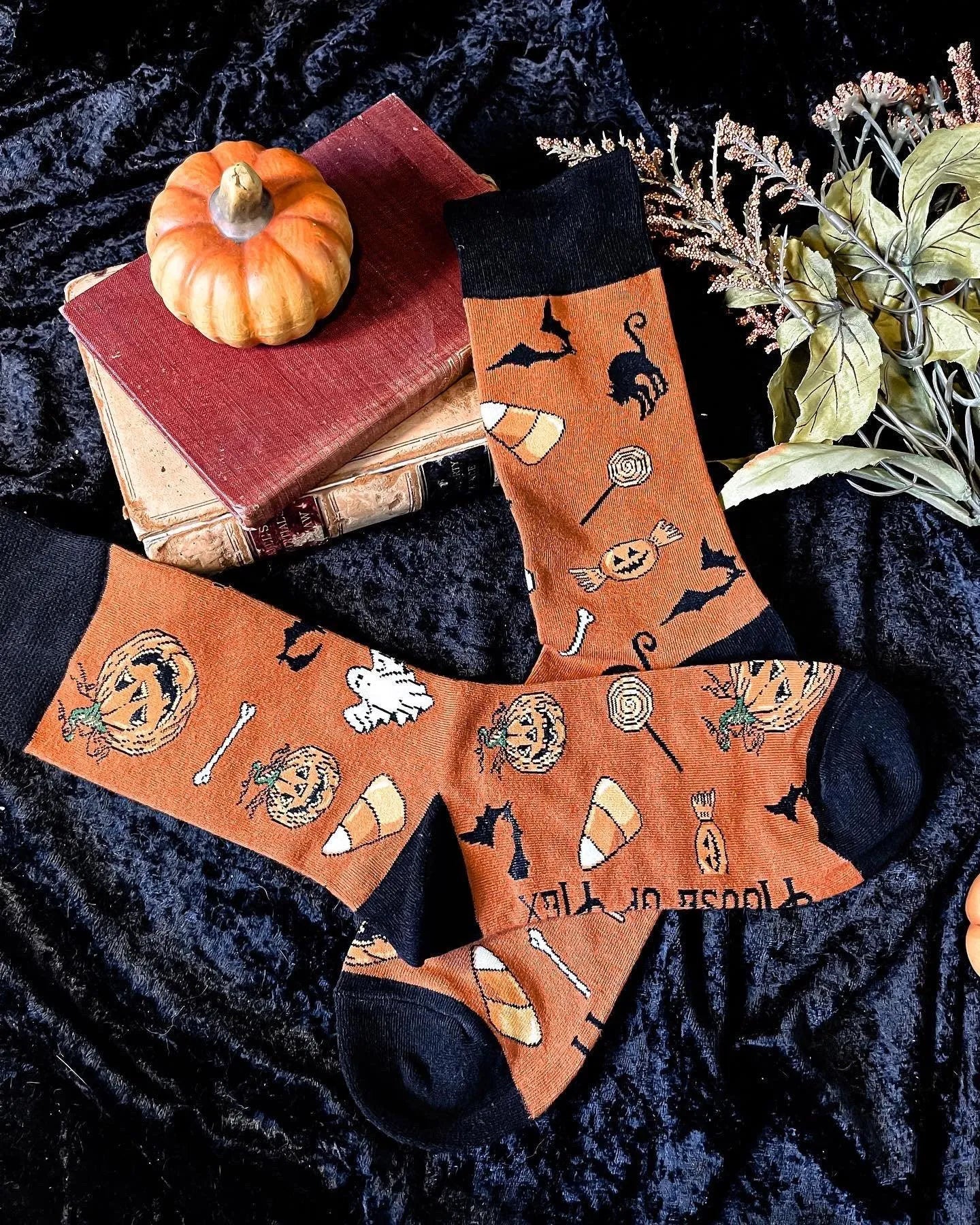 Halloween socks with blacks on the toes, heel, and ankle section featuring a pattern of pumpkins, candy corn, ghosts, bones, and bats.