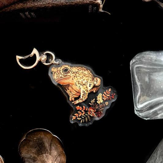 Keychain featuring a vibrant gold frog over a bouquet of flowers with a golden Moon clasp at the top.