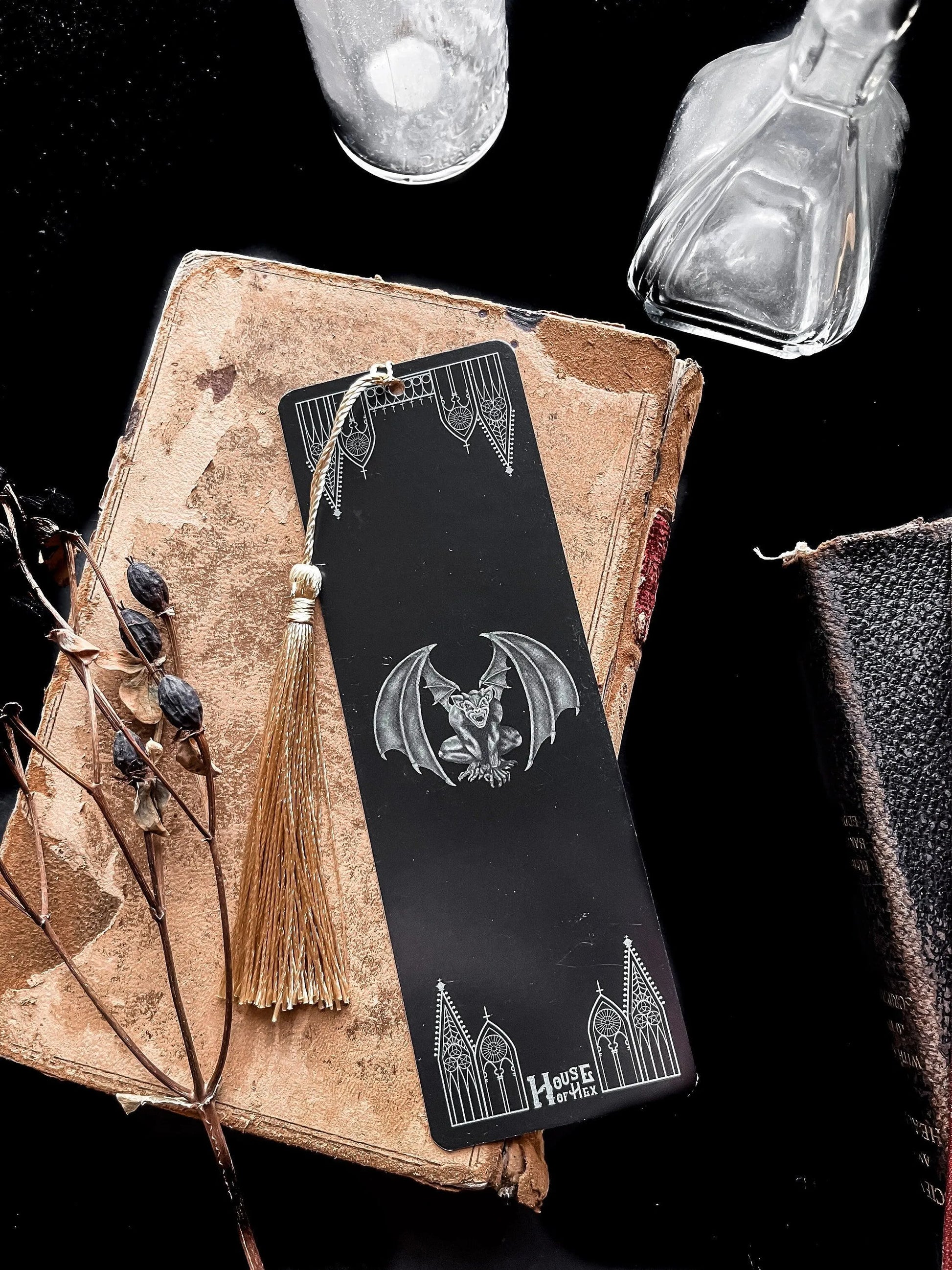 A decorative bookmark featuring a Gargoyle and gables on a black background with a gold tassel.