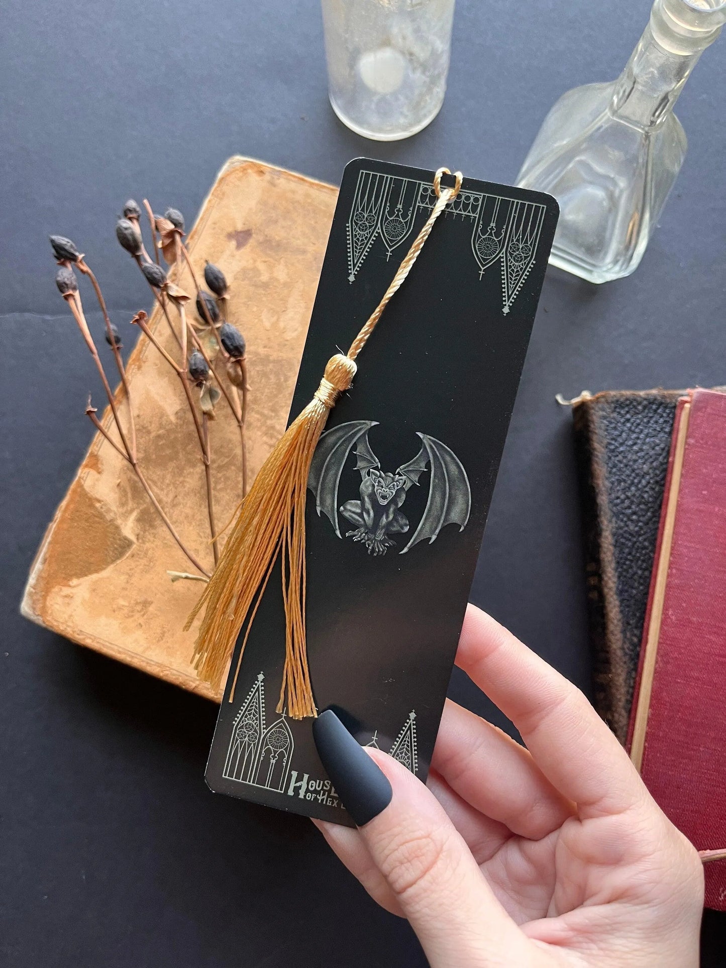 A decorative bookmark featuring a Gargoyle and gables on a black background with a gold tassel.