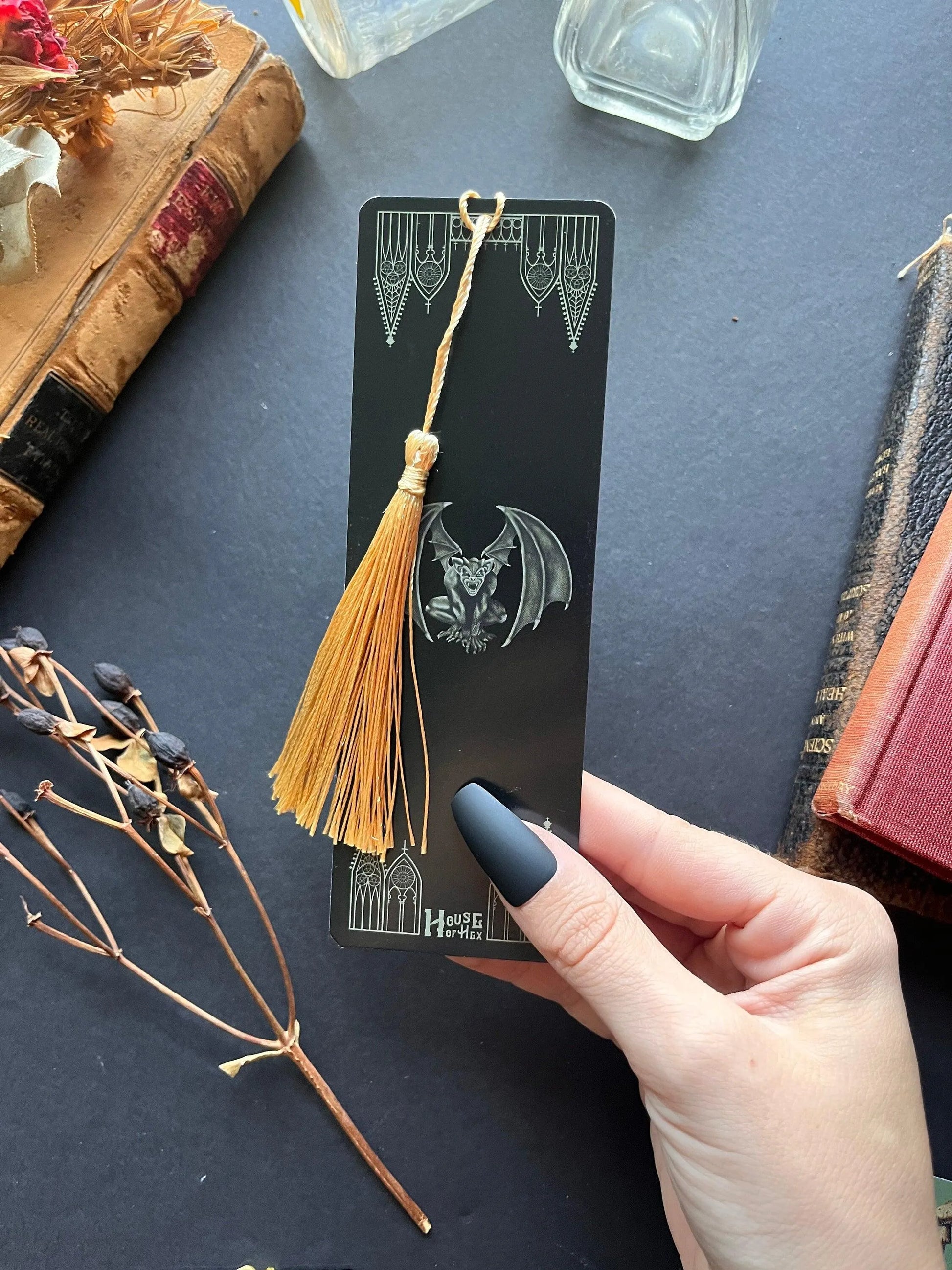 A decorative bookmark featuring a Gargoyle and gables on a black background with a gold tassel.