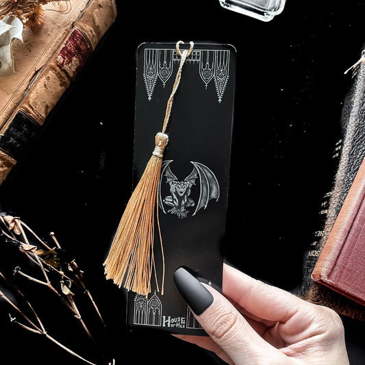 A decorative bookmark featuring a Gargoyle and gables on a black background with a gold tassel.