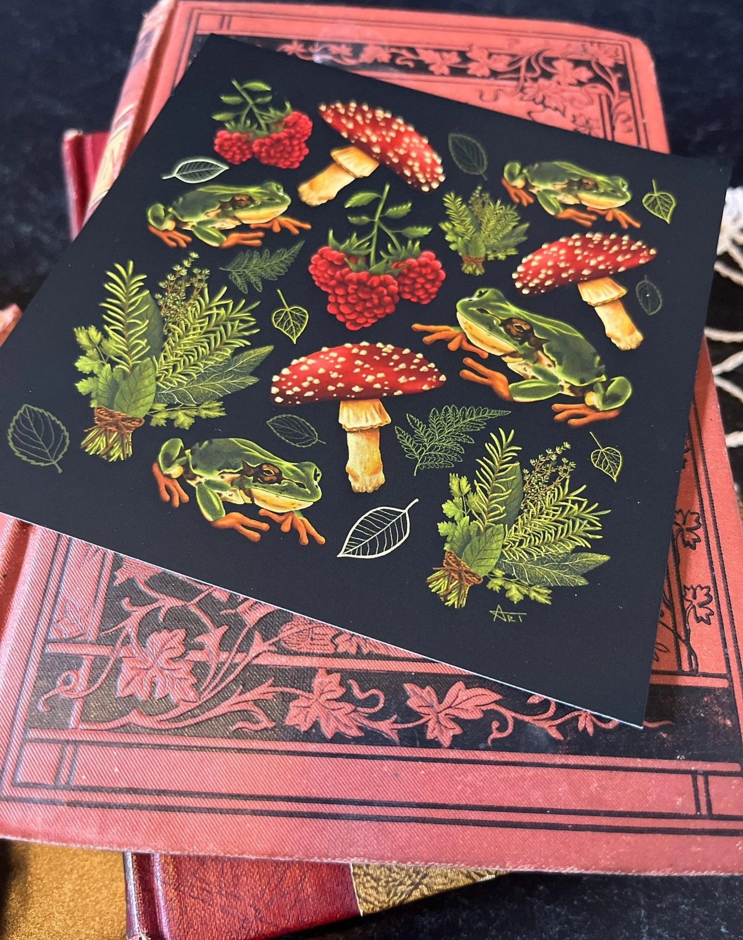 A decorative square print featuring a pattern of mushrooms, plants, and frogs on a black background.