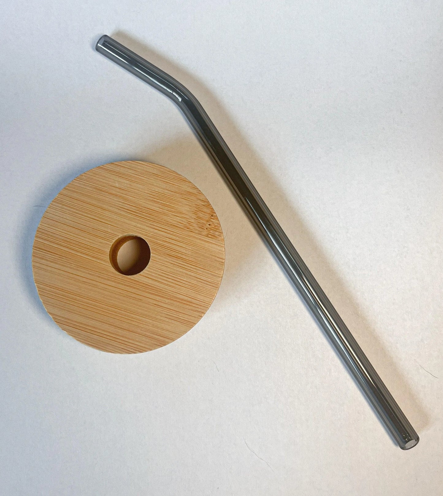 Bamboo lid and black glass straw for a drinking glass.
